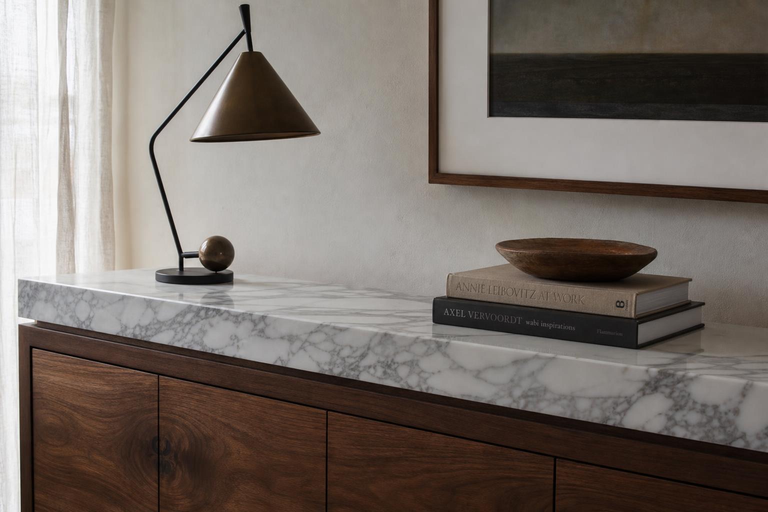 Walnut console with a white marble top and a sculptural black metal lamp in soft daylight